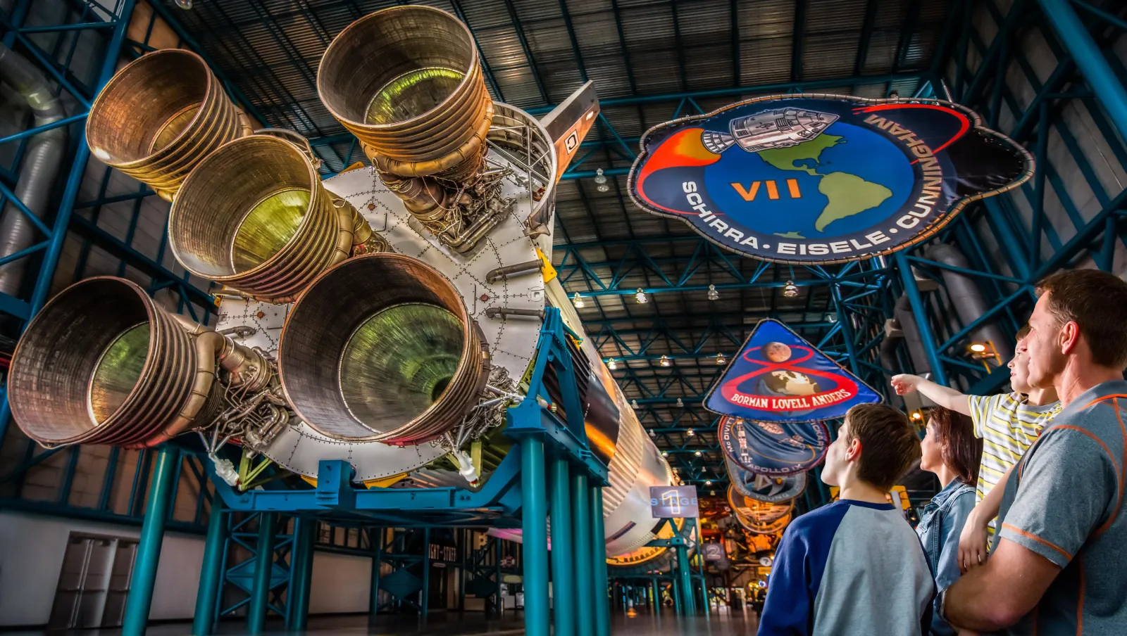 Family looking up at the Saturn V engines and Apollo mission patches in the Apollo/Saturn V Center