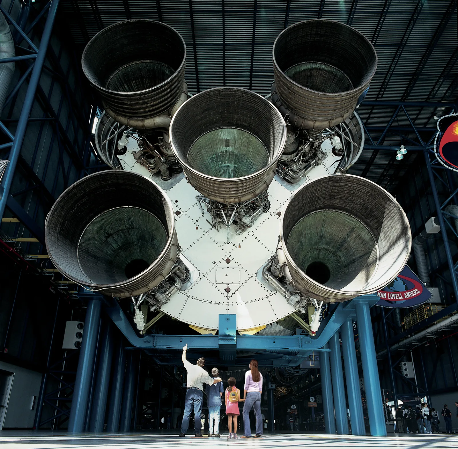 Family standing beneath the five huge engine bells of the Saturn V rocket in the Apollo/Saturn V Center