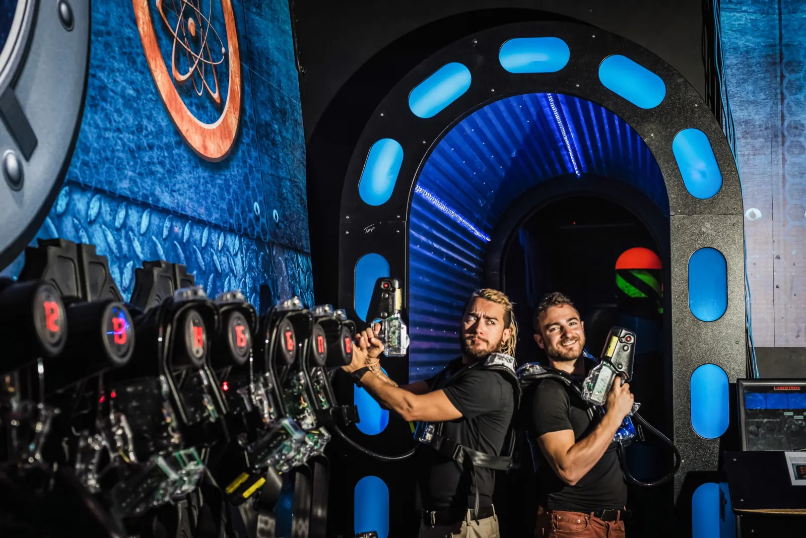 Two players in laser tag vests holding blasters at the entrance to the laser tag arena