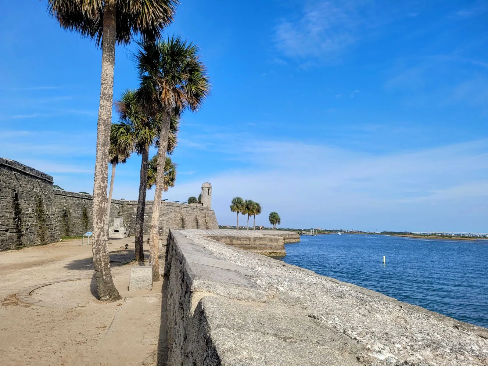 Coquina stone walls and watchtower of Castillo de San Marcos beside Matanzas Bay under a blue sky