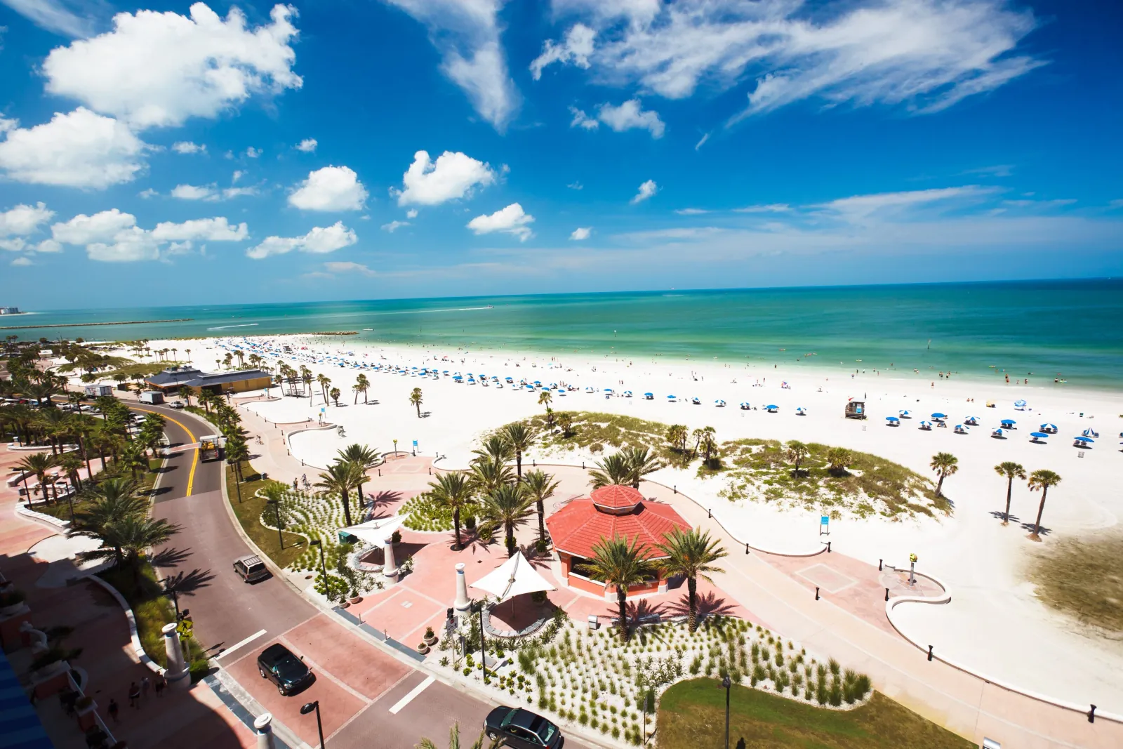 Aerial view of Clearwater Beach with white sand, rows of blue umbrellas and the turquoise Gulf