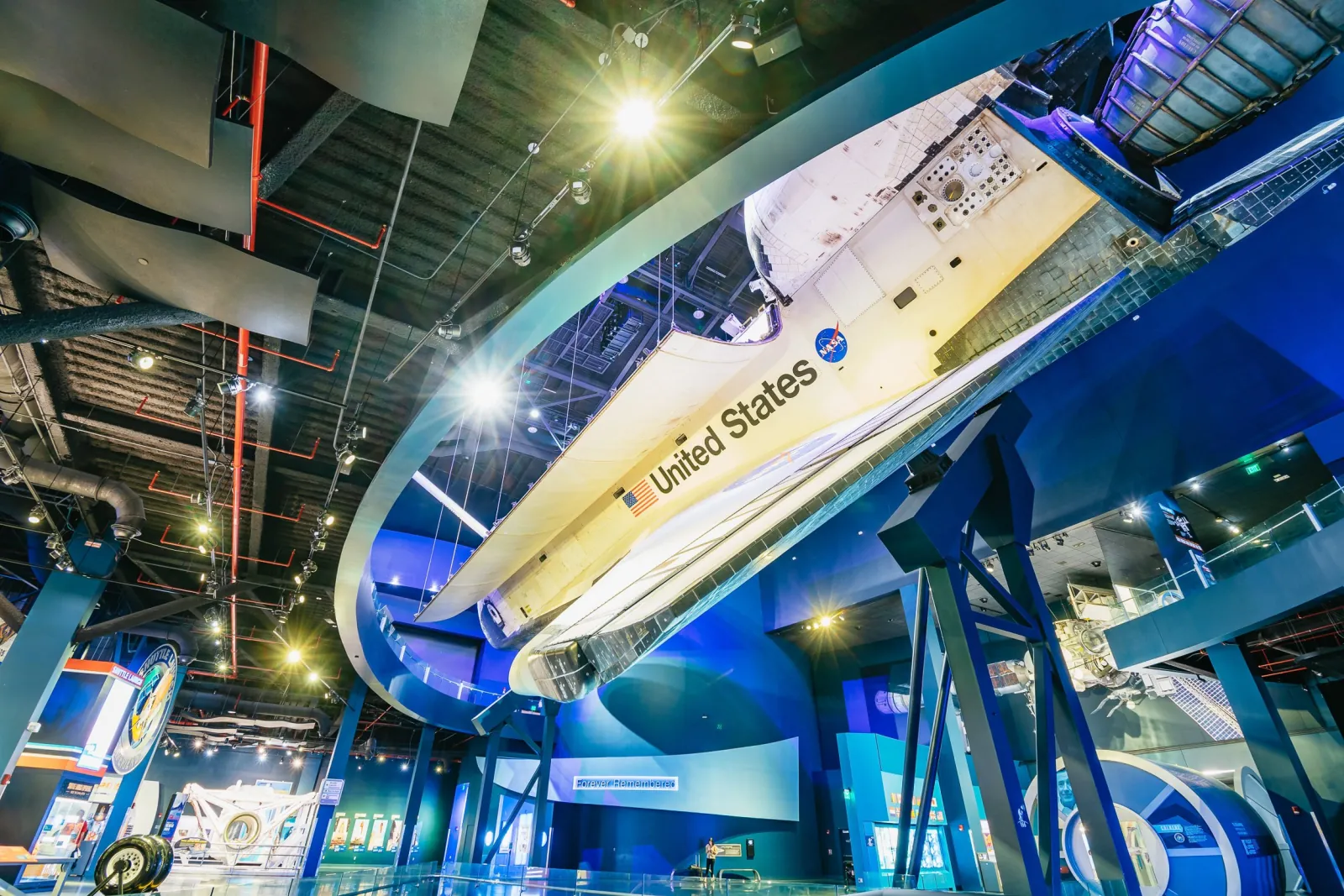 Space Shuttle Atlantis suspended at an angle inside its exhibit hall, with the United States lettering on its wing