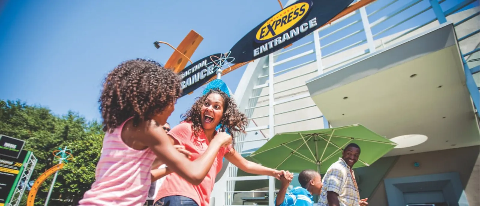 Family laughing outside a ride building under a blue 'Universal Express Entrance' sign