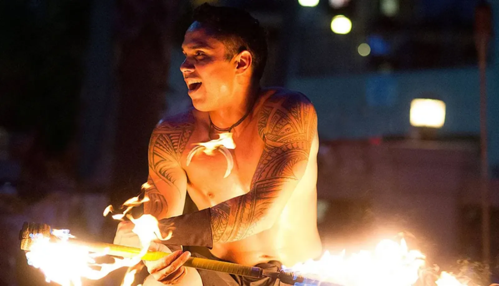 Tattooed performer holding a fire knife with both ends alight