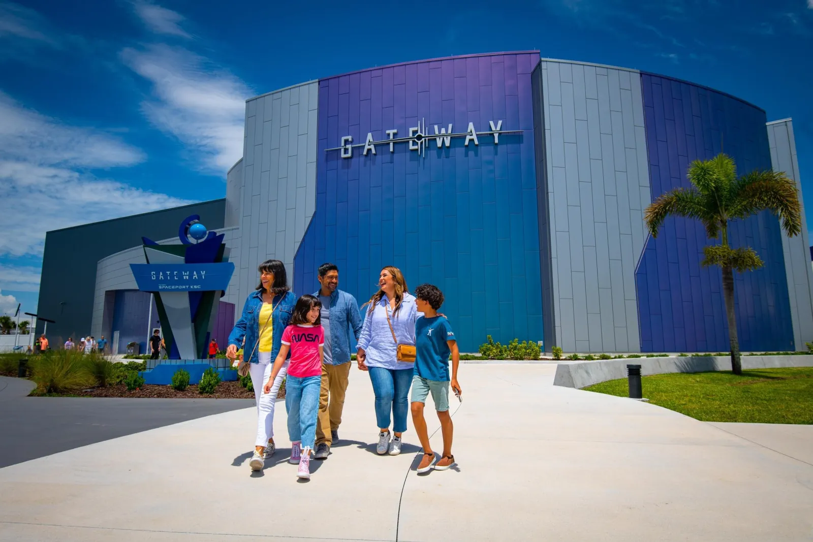 Family walking out of the purple and silver Gateway building at the Kennedy Space Center Visitor Complex