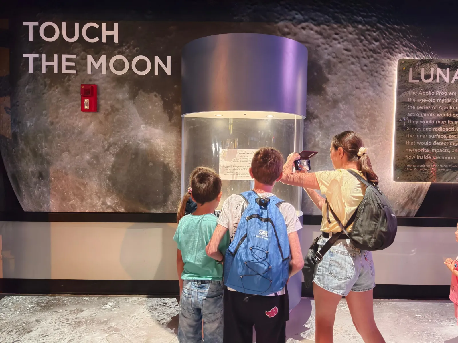 Children and a woman photographing the lunar sample case at the 'Touch the Moon' exhibit