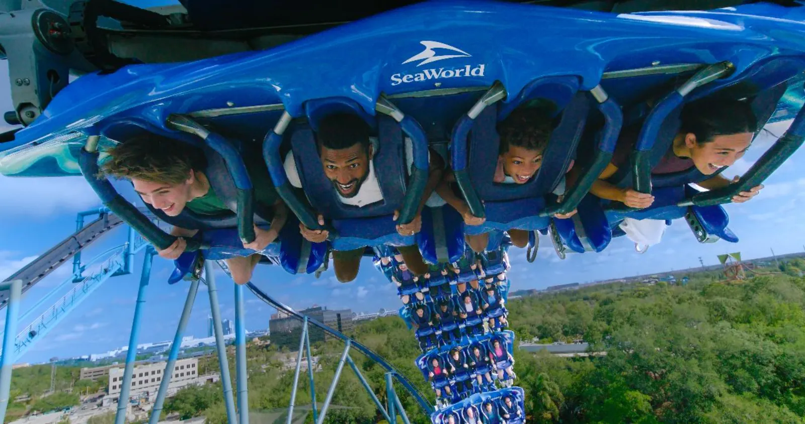 Riders lying face down in the flying-style seats of the Manta coaster above the park's treetops
