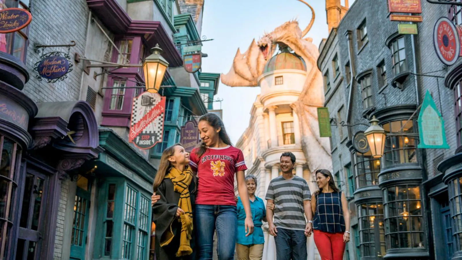 Family walking through Diagon Alley, with the dragon perched on top of Gringotts bank behind them